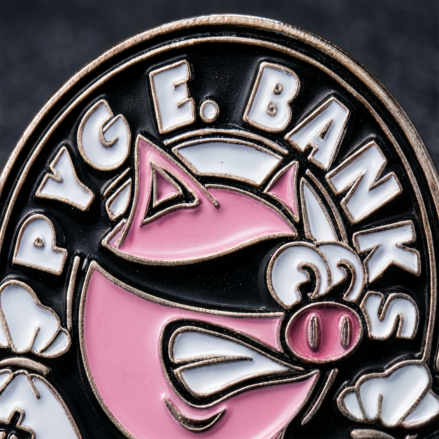 Close-up of a badge with 'pyge Banks' text and pink and white design elements on a dark background