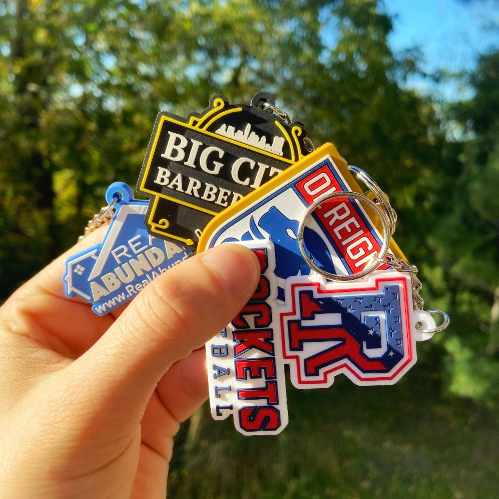 Hand holding four custom keychains made from rubber with logo