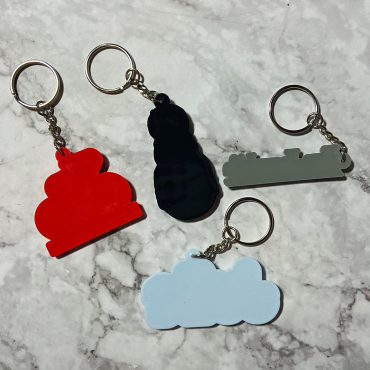 Back view of custom PVC promotional keychains in various shapes and colors, attached to metal keyrings, displayed on a marble background.