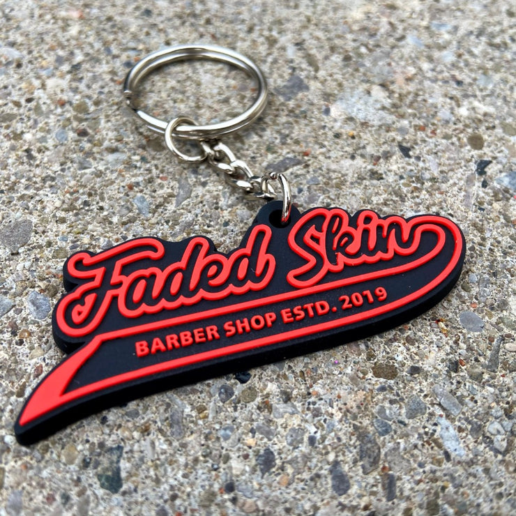 Promotional barber shop rubber 3d pvc keychain with 'Faded Skin' logo, custom rubber material, black and red design, attached to a silver keyring.